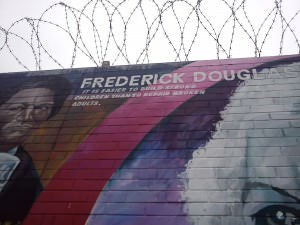 Frederick Douglas political mural in Belfast, topped with barbed wire