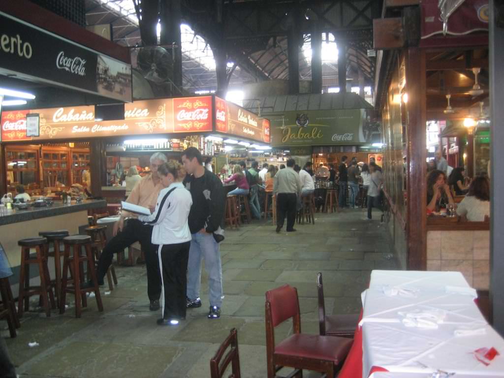 Montevideo, Uruguay's Mercado del Puerto (meat market) famous for fantastic and cheap fast food steak meals at every turn. Flights to Montevideo are limited but a ferry connects the Uruguay capital with Buenos Aires, Argentina which has more flight options. how to book the cheapest flight