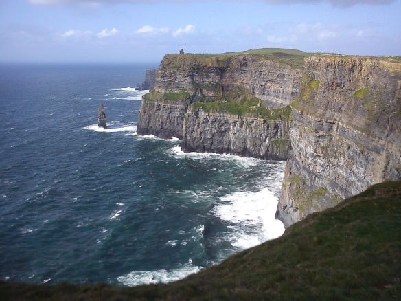 Cliffs of Moher in County Clare with sea and waves and castle off in the distance