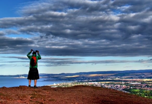 a hiker admiring the view overlooking Edinburgh from summit of Arthur's Seat