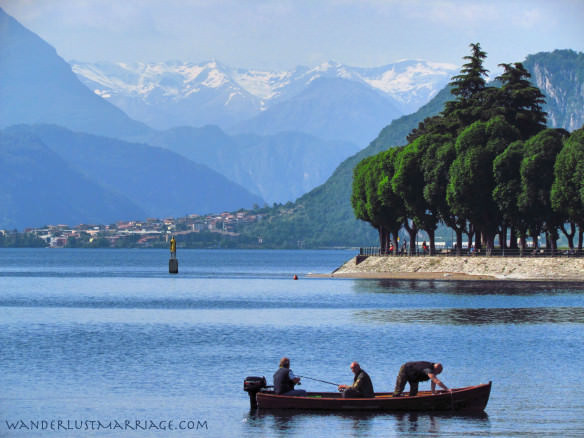 Men fishing on Lake Como with snow capped mountains in the background