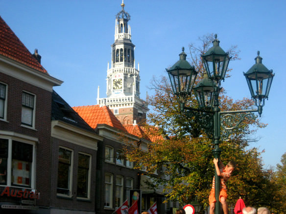 Dutch kid climbing a light post with a beautiful church in the background