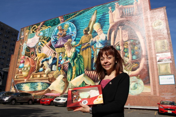 Bell posing with an assorted box of Beiler's donuts in front of a Philadelphia mural