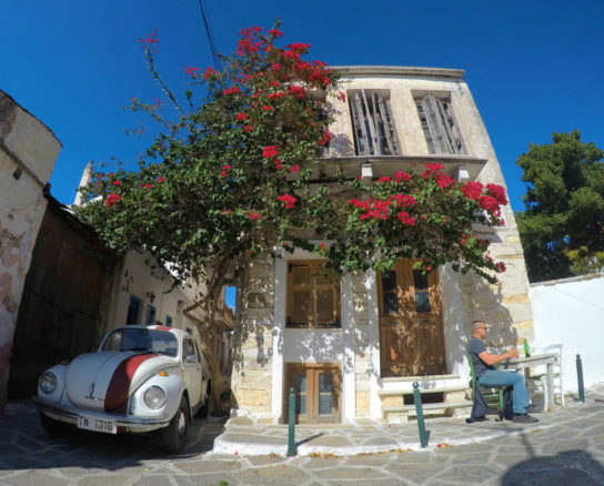 House with bright red flowers, blue sky and a VW betel car