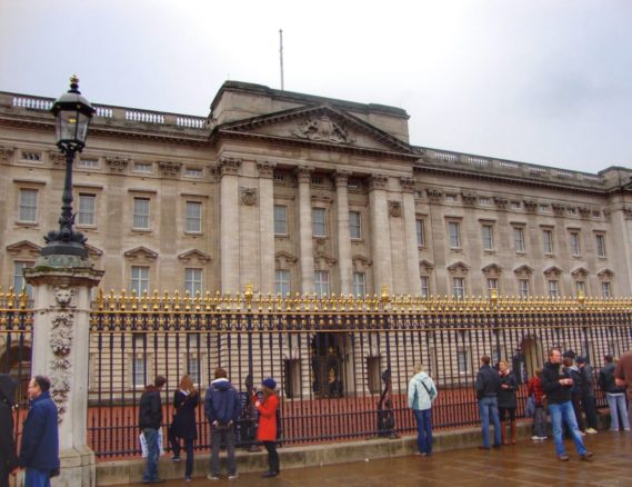 people standing outside the gate of Buckingham Palace in London, England