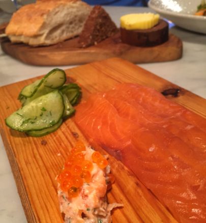 Board with smoked salmon and bread in background