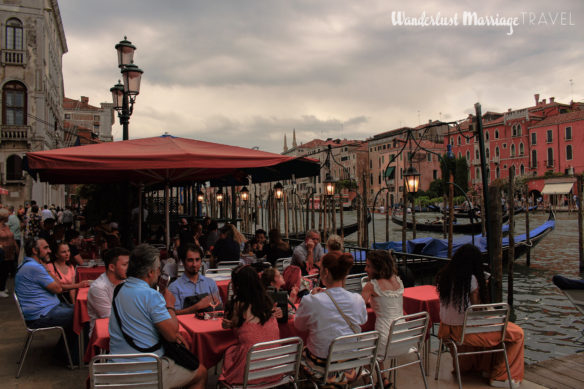 People enjoying a cafe terrace on the canals of Venice, Italy