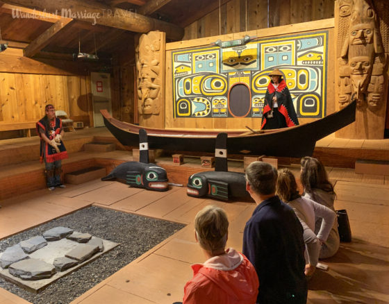 Member of the Tlingit tribe telling their story in the cedar wood tribal house