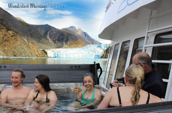 Bell and Uncruise guests enjoying the hot tub and drinks in front of a glacier