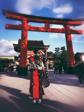 Japanese women dressed in a kimono under a red Torri gate at Fushimi Inari Taisha in Kyoto 