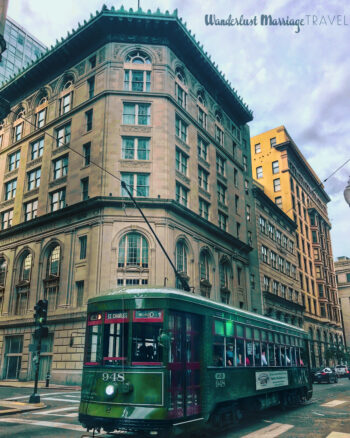 Green street car in the streets on New Orleans with tall buildings