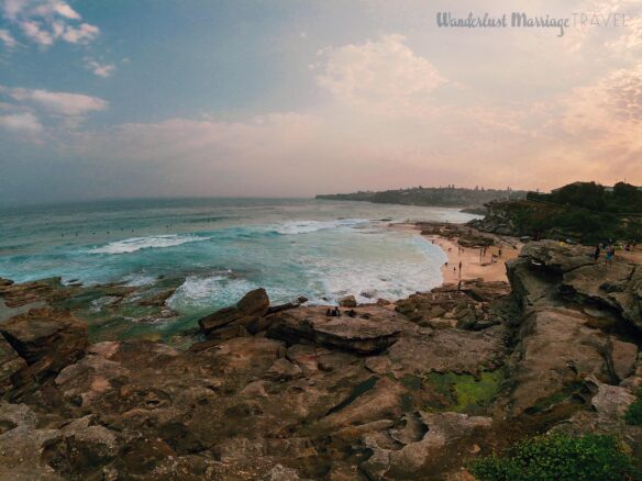 Picture of rocks and the ocean, with cityscape off in the background