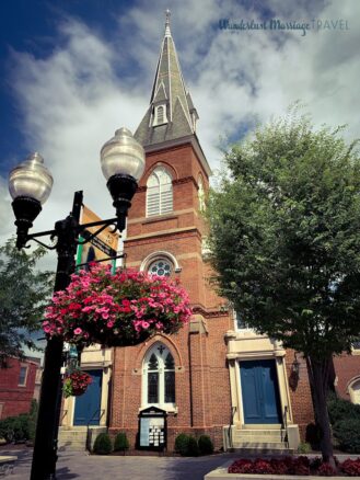 Picture of a red brick church with a lamp post and flower basket filled with pink flowers