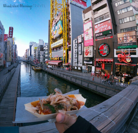 Holding Takoyaki (fried octopus balls) on the Dotonbori Canal in Osaka, Japan