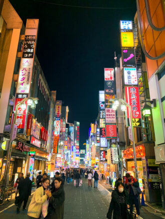 the many shops and bustling crowds of the Shinjuku district in Tokyo, Japan