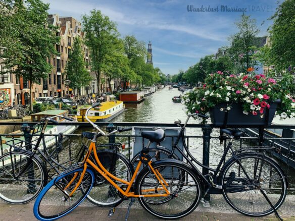 Amsterdam canal with bikes on a bridge and a blue sky