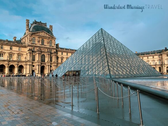 A glass pyramid in front of the Louvre Museum after it has just rained