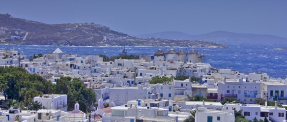view of the island of Mykonos, including the row of 16th century windmills above the white washed town
