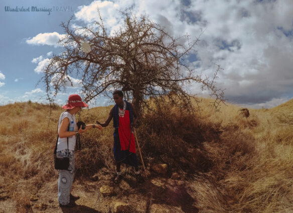 A Maasai warrior is explaining and showing Bell how they use the milk from a certain type of tree on their skin