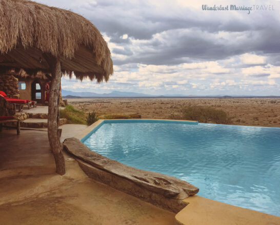 A swimming pool over looking the plains with a cloudy sky