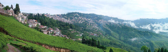 Mountains, with low hanging wispy clouds, and homes nestled in the mountain side