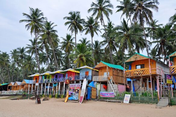 Colorful beach shacks surrounded by palm tress and sand