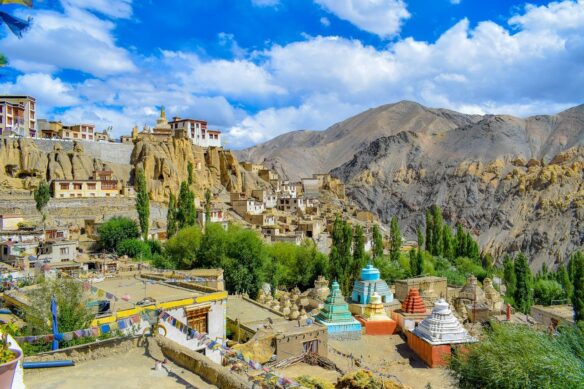 Arid mountains with a colorful village perched a top one mountain with a blue sky and white clouds 