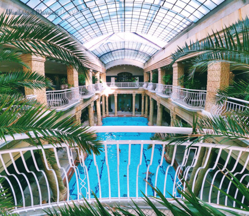 Photo overlooking people swimming in the Gellert Spa indoor thermal pool in Budapest, Hungary.