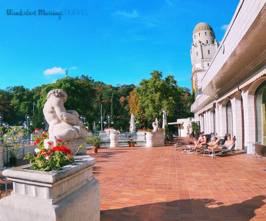 3 guys sitting in lounge chairs on the Gellert Spa outdoor terrace.