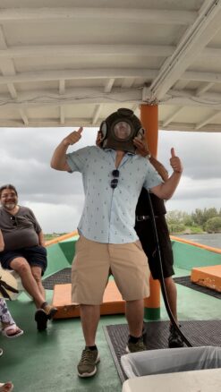 Alex wearing an old sponge diving helmet on a  St. Nicolas Boatline sponge history tour in Tarpon Springs 