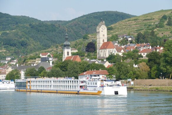 The Danube river with a cruise ship and the village of Krems in the background where you can see church spires and homes