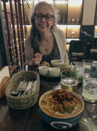 Bowl of soupy rice and a plate with fried chicken and Bell ready to dive into this feast