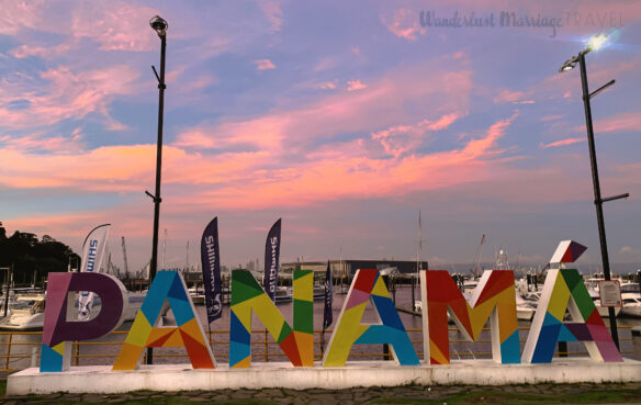 Large, colorful letters spelling out Panama in front of the water and the sun setting