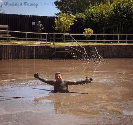 Alex sitting in a mud pit with beautiful blue skies