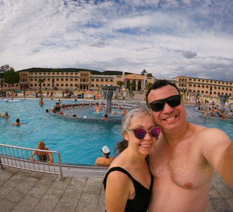 Alex and Bell standing in front of the pool with the bathhouse in the background