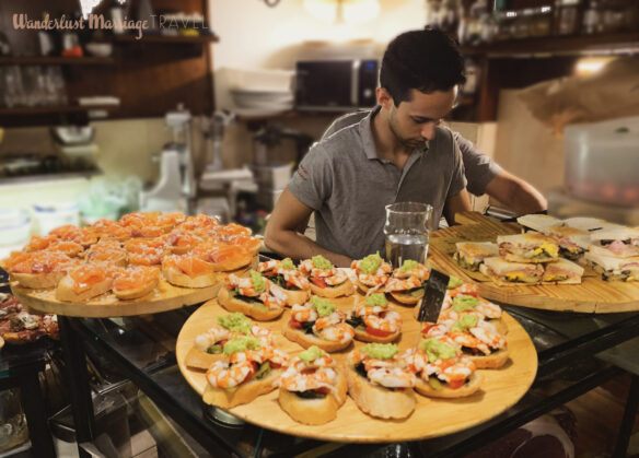 three platters of open face sandwiches and a server prepping more food