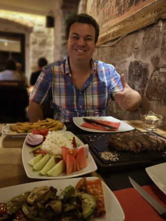 Alex giving the thumbs up to a romantic dinner of steak and salad that sits on the table in front of him