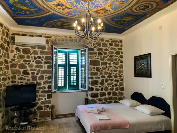 Stone walls, and a beautiful motif painted on the roof of this bedroom with a flatscreen TV