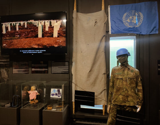 Exhibit at the museum of crimes against humanity, with UN flag, and a screen showing a mass burial plot