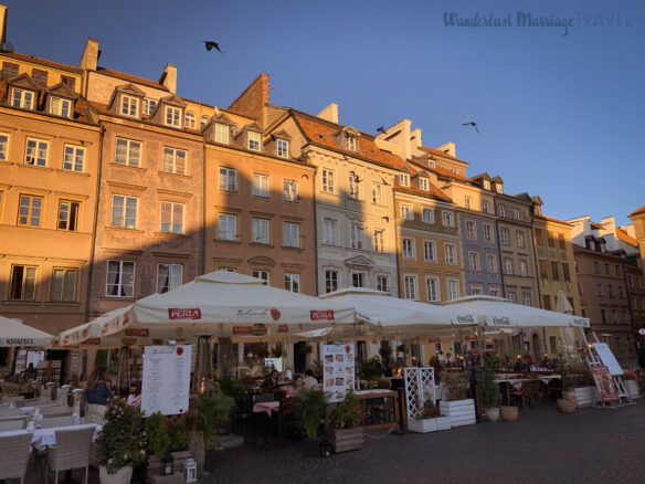 Colorful buildings with outdoor terraces set up with tables and umbrellas in Poland's capitol of Warsaw