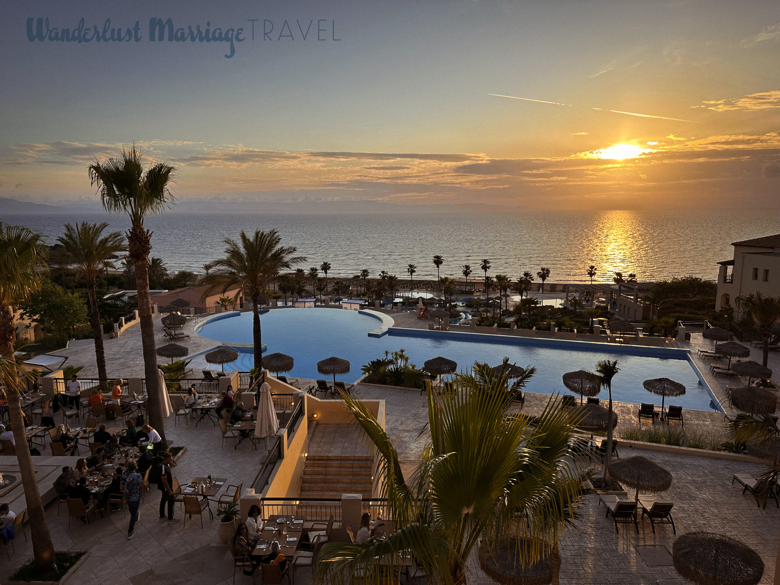 Sunsetting over the resort pool with people sitting and eating dinner