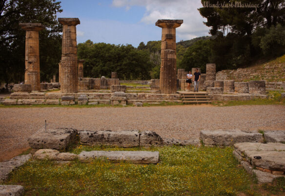 A couple walk throw the column ruins with blue skies