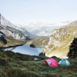 Two tents with a beautiful view overlooking a lake and mountains, in between two mountains