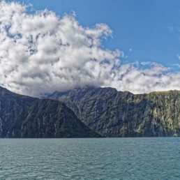 The beautiful fjords in Milford Sound, New Zealand with partly cloudy blue skies.