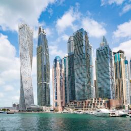 Tall skyscapers along Dubai Marina, with a partly cloudy blue sky.