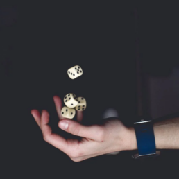 three dice thrown in the air with a dark backdrop.