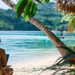 A girl sitting on the beach under a tree in a tropical destination.