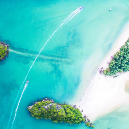 A small tropical island beach surrounded by clear turquoise water.