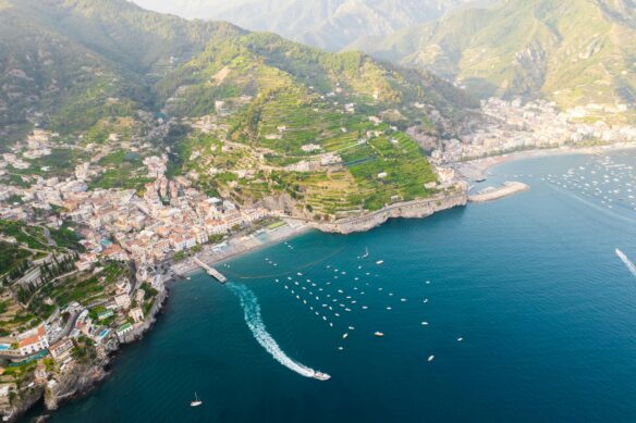 Amalfi coast towns set along the mountains and sea, with a ship sailing out.