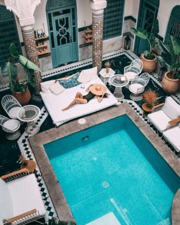 A woman relaxing my a pool lined with ornate architecture in Marrakech, Morocco.